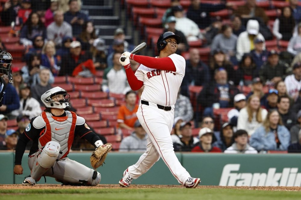 Boston Red Sox's Rafael Devers, right, follows through on a grand slam against the Baltimore Orioles during the eighth inning in the first baseball game of a doubleheader Friday, May 23, 2025, at Fenway Park in Boston. (AP Photo/Winslow Townson)