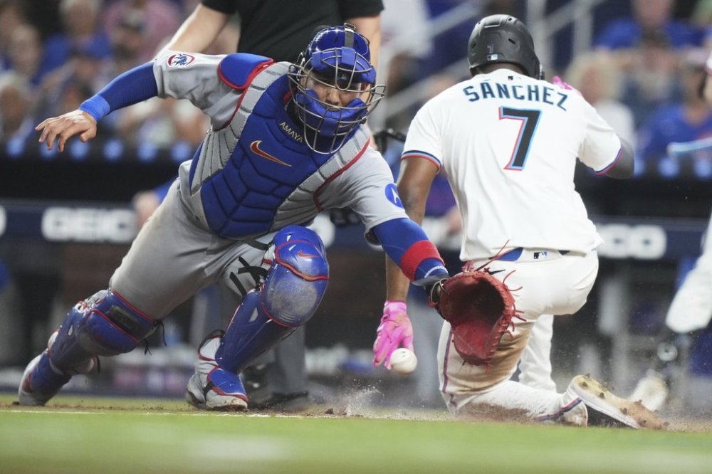 Miami Marlins' Jesus Sanchez (7) beats the throw to Chicago Cubs catcher Miguel Amaya, left, to score on a single hit by Otto Lopez during the fifth inning of a baseball game Monday, May 19, 2025, in Miami. (AP Photo/Lynne Sladky)