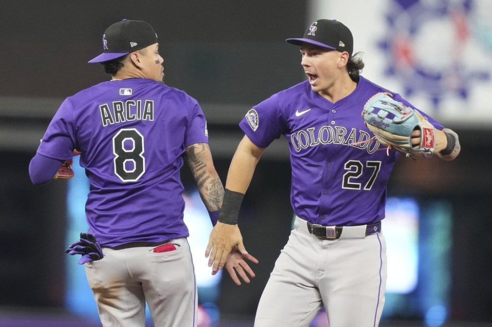 Colorado Rockies shortstop Orlando Arcia (8) and left fielder Jordan Beck (27) high-five after the Rockies defeated the Miami Marlins in a baseball game, Wednesday, June 4, 2025, in Miami. (AP Photo/Lynne Sladky)