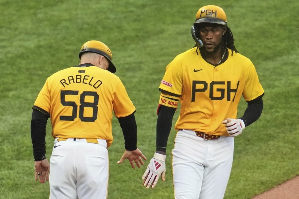 Pittsburgh Pirates' Oneil Cruz, right, celebrates with third base coach Mike Rabelo (58) as he rounds third after hitting a solo home run off Milwaukee Brewers pitcher Freddy Peralta during the third inning of a baseball game in Pittsburgh, Friday, May 23, 2025. (AP Photo/Gene J. Puskar)