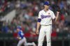 Texas Rangers starting pitcher Jacob deGrom, right, waits for a new ball as Toronto Blue Jays' Daulton Varsho, left, runs the bases after hitting a solo home run during the first inning of a baseball game, Monday, May 26, 2025, in Arlington, Texas. (AP Photo/Julio Cortez)