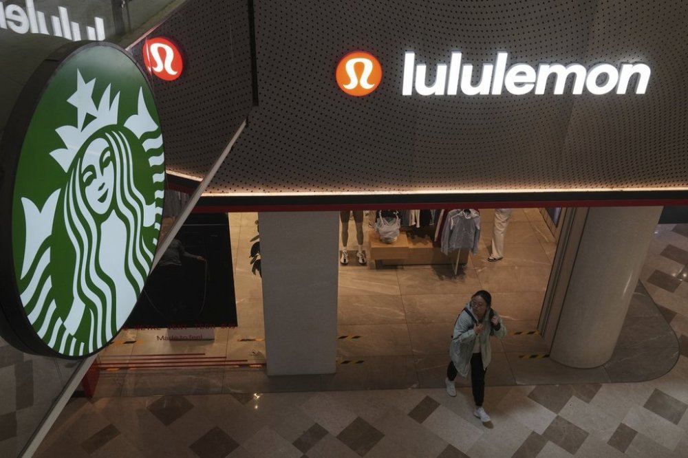 A woman walks out from a Lululemon store next to Starbucks café inside a shopping mall, in Beijing, Thursday, April 10, 2025. (AP Photo/Andy Wong)