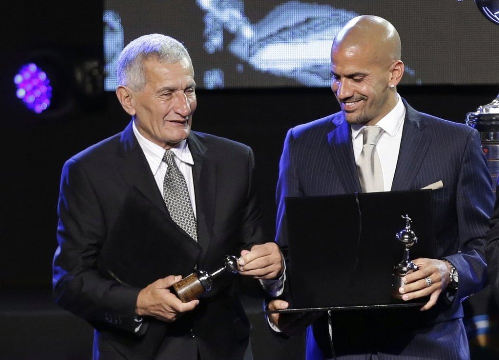 FILE - Juan Ramon Veron and his son Sebastian Veron are honored during the Copa Libertadores' draw ceremony in Luque, Paraguay, Dec. 2, 2014. Verón, who scored a goal against Manchester United at Old Trafford to help Argentina's Estudiantes La Plata win the 1968 Intercontinental Cup, died on Tuesday, May 27, 2025, his former team said. He was 81. (AP Photo/Jorge Saenz, File)