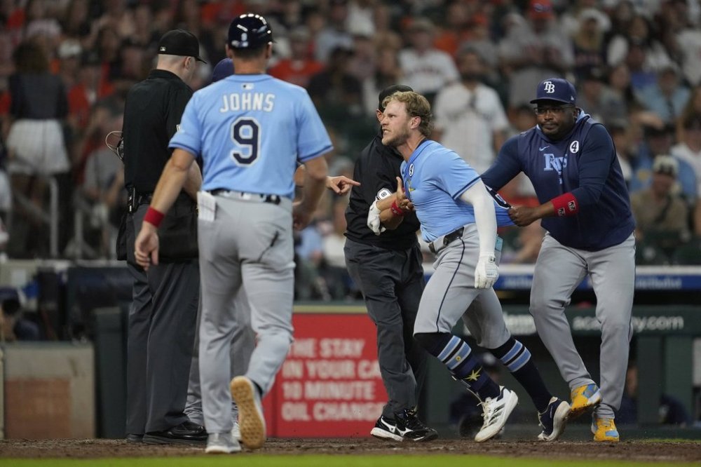 Tampa Bay Rays' Taylor Walls, center, is held back after he's ejected by Umpire Nic Lentz, left, for tapping his helmet after a strike call during the ninth inning of a baseball game against the Houston Astros in Houston, Sunday, June 1, 2025. (AP Photo/Ashley Landis)