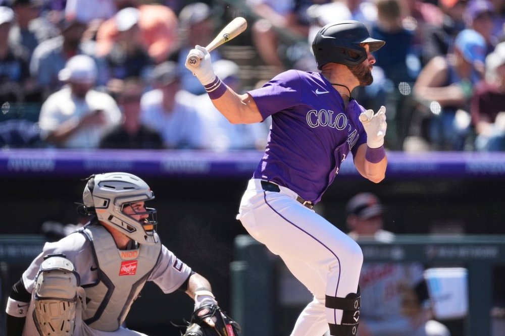 Colorado Rockies' Nick Martini, right, hits a single as Detroit Tigers catcher Tomás Nido looks on during the fifth inning in the first baseball game of a doubleheader Thursday, May 8, 2025, in Denver. (AP Photo/David Zalubowski)