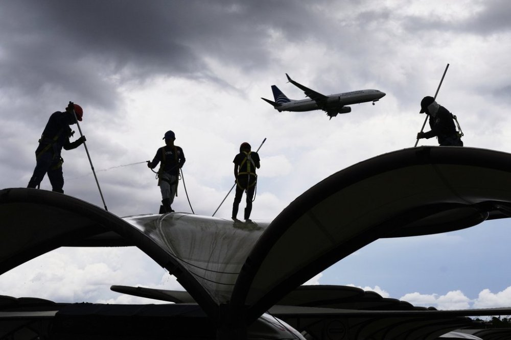 Workers clean a roof at the Tocumen International Airport in Panama City, Thursday, May 22, 2025, as Panama and Venezuela prepare to resume commercial flights nearly a year after suspending them when Panamanian President Jose Raul Mulino refused to recognize the re-election of Venezuelan President Nicolas Maduro. (AP Photo/Matias Delacroix)