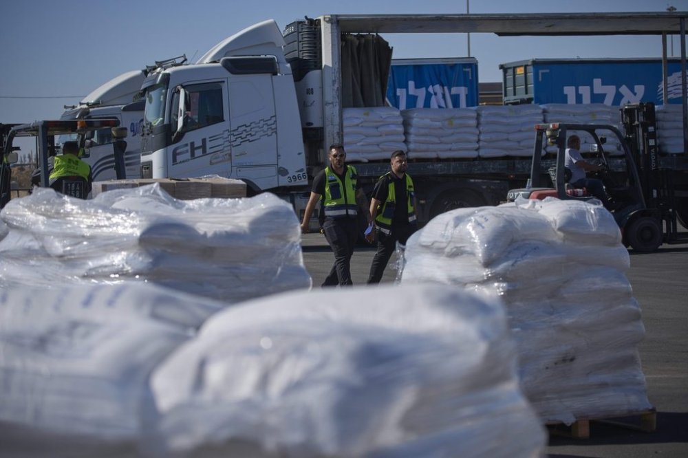 Workers walk past a truck carrying humanitarian aid for the Gaza Strip parked at the offload area of the Kerem Shalom border crossing between Israel and Gaza, southern Israel, Thursday, May 29, 2025. (AP Photo/Ohad Zwigenberg)