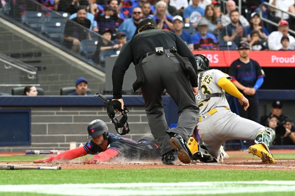 Blue Jays infielder Ernie Clement (22) slides safely into home ahead of a tag by Athletics catcher Shea Langeliers (23) in the second inning of a Major League Baseball game in Toronto on Friday, May 30, 2025. THE CANADIAN PRESS/Jon Blacker