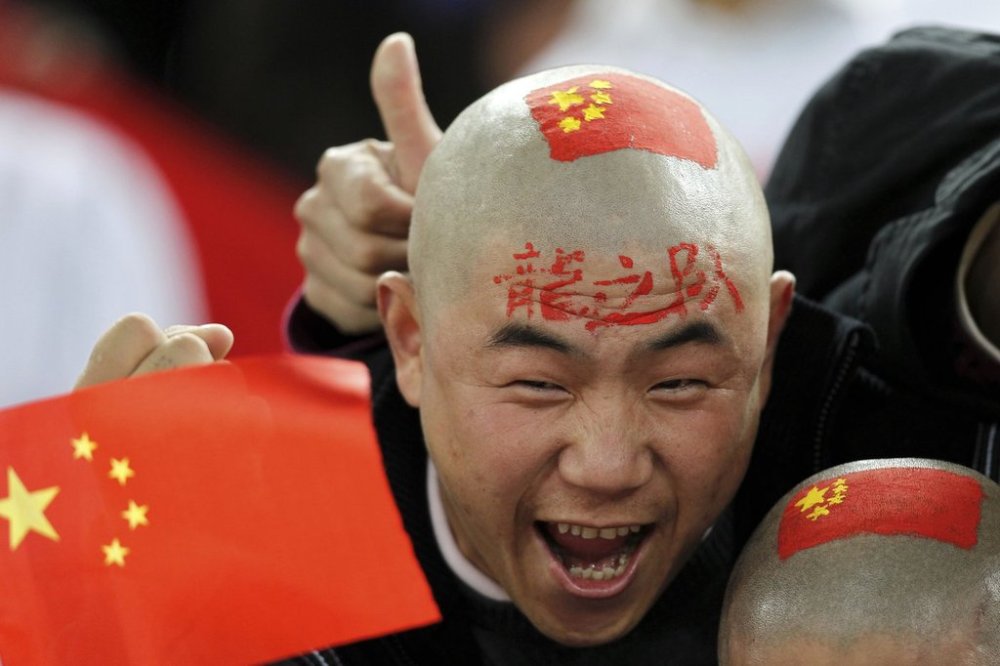FILE - A Chinese soccer fan cheers for his team before their AFC Asian Cup group A soccer match against Qatar in Doha, Qatar, on Jan. 12, 2011. (AP Photo/Hassan Ammar, File)