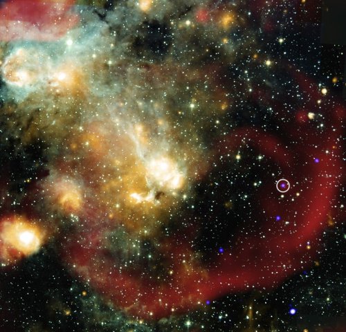 This image provided by NASA shows X-rays from NASA’s Chandra X-ray Observatory (represented in blue) that have been combined with infrared data from NASA’s retired Spitzer Space Telescope (cyan, light blue, teal and orange), and radio from MeerKat (red). An inset shows a more detailed view of the immediate area around this unusual object in X-ray and radio light. (NASA/Chandra/Spitzer/MeerKat via AP)