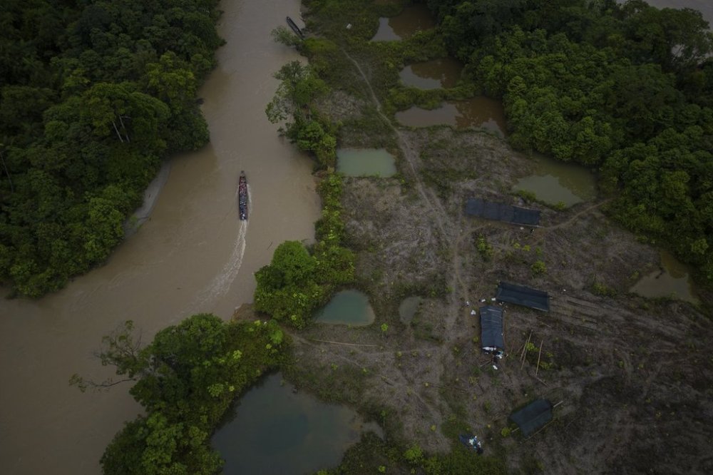 FILE - A boat, with gasoline to be taken to illegal mining machinery, maneuvers past an area that was mined near Paimado, Colombia, Sept. 24, 2024. (AP Photo/Ivan Valencia, File)