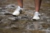 A fan walks through a soggy puddle near the 14th hole during the third round of the U.S. Open golf tournament at Oakmont Country Club Saturday, June 14, 2025, in Oakmont, Pa. (AP Photo/Charlie Riedel)