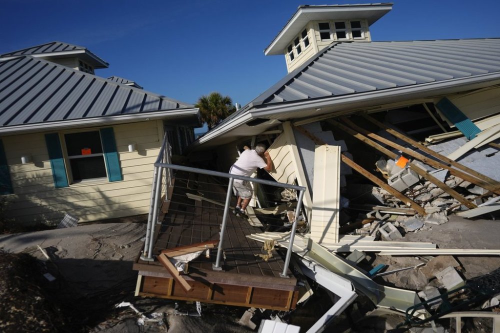 FILE - A property owner, who preferred not to give his name, peers into the remains of the second floor unit where he lived with his wife while renting out the other units, on Manasota Key, in Englewood, Fla., following the passage of Hurricane Milton, Oct. 13, 2024. (AP Photo/Rebecca Blackwell, File)
