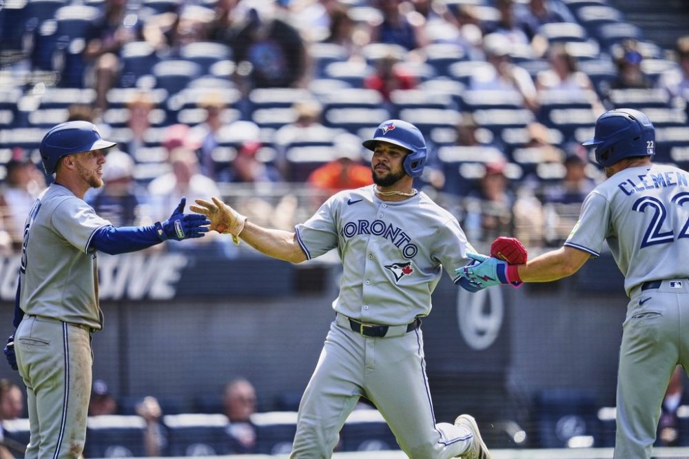 Toronto Blue Jays' Jonatan Clase, centre, is greeted by Myles Straw, left, and Ernie Clement (22) after scoring in the ninth inning of a baseball game against the Cleveland Guardians in Cleveland, Thursday, June 26, 2025. (AP Photo/Sue Ogrocki)