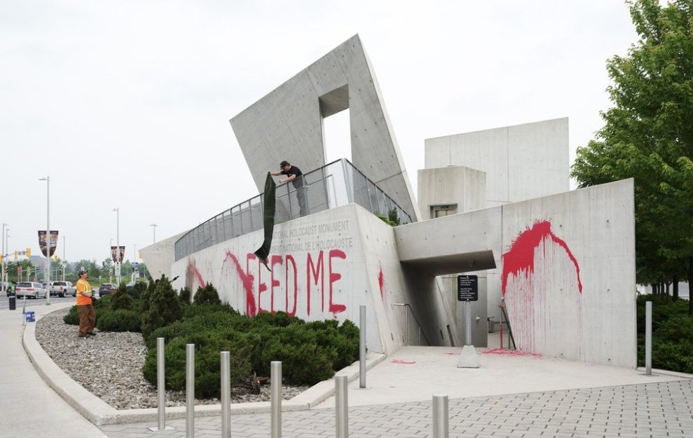 Workers from a cleanup crew spread a tarp to cover the words 'FEED ME' on the National Holocaust Monument in Ottawa on Monday, June 9, 2025. THE CANADIAN PRESS/Sean Kilpatrick