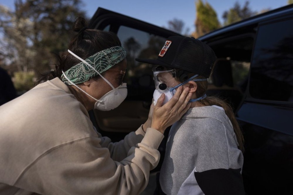 FILE - Eaton Fire evacuee Alyson Granaderos, left, sobs while trying to comfort her son, Ceiba Phillips, 11, as he visits their home for the first time since the fire in Altadena, Calif., Feb. 8, 2025. (AP Photo/Jae C. Hong, File)