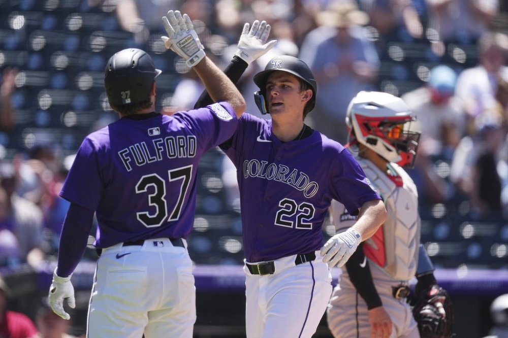 Colorado Rockies' Braxton Fulford, left, congratulates Mickey Moniak as he crosses home plate after hitting a three-run home run off Arizona Diamondbacks starting pitcher Brandon Pfaadt in the fifth inning of a baseball game Sunday, June 22, 2025, in Denver. (AP Photo/David Zalubowski)