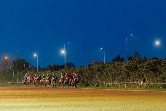 Jockeys, including Ciera Pruitt, and their horses walk out to the gate for the last race of the evening. (Mike Deal / Free Press)