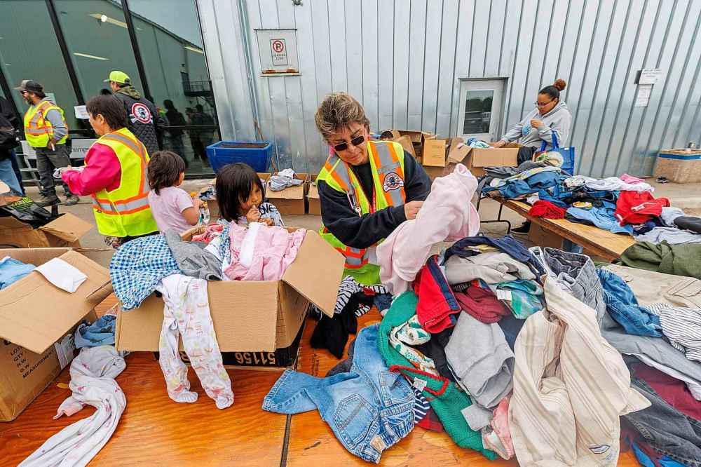 Volunteer Sandra Trottier with MMF looks for a sweater for a client outside the evacuation centre in Thompson