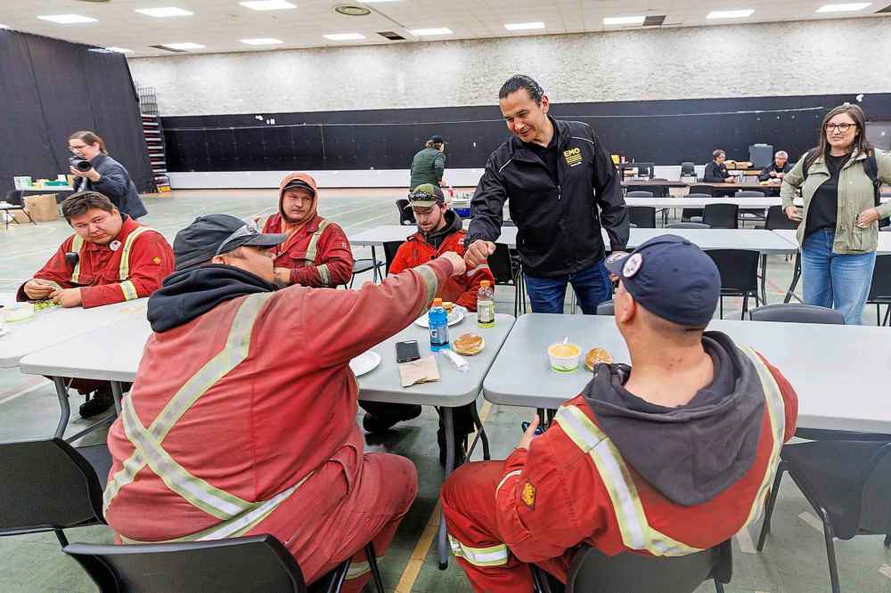Premier Wab Kinew chats with firefighters from the Ebb and Flow Fire Department while they eat lunch at the R.H. Channing Auditorium (Community Hall) in Flin Flon.