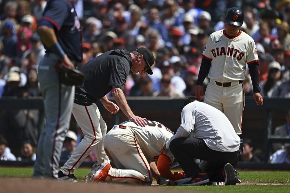 San Francisco Giants manager Bob Melvin (6) checks on Matt Chapman (26) after injuring himself on a play in the eighth inning of a baseball game against the Atlanta Braves at Oracle Park in San Francisco, Sunday, June 8, 2025. (Jose Carlos Fajardo/Bay Area News Group via AP)