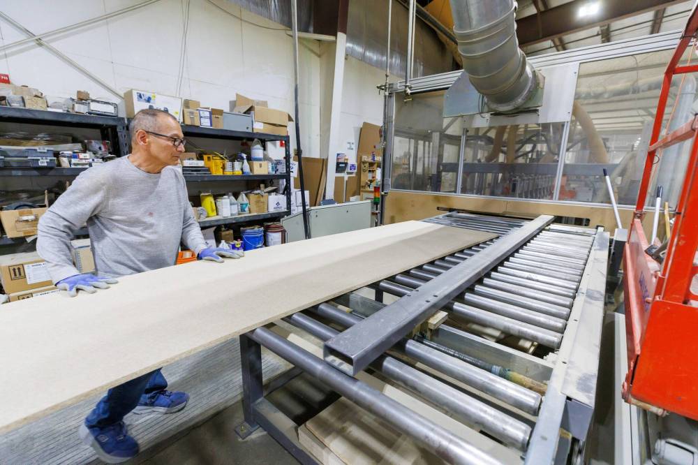 MIKE DEAL / FREE PRESS
Corebuilder operator Ariel feeds a countertop into a machine that creates a bevelled edge.