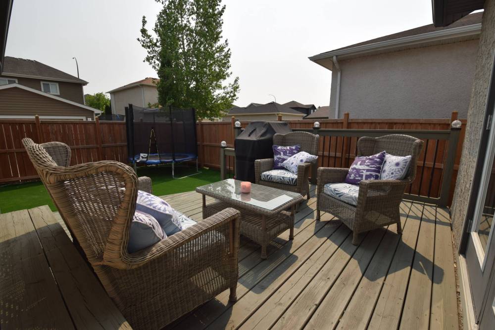 A two-tiered deck with barbecue area looks out onto a private, low-maintenance backyard with play area.