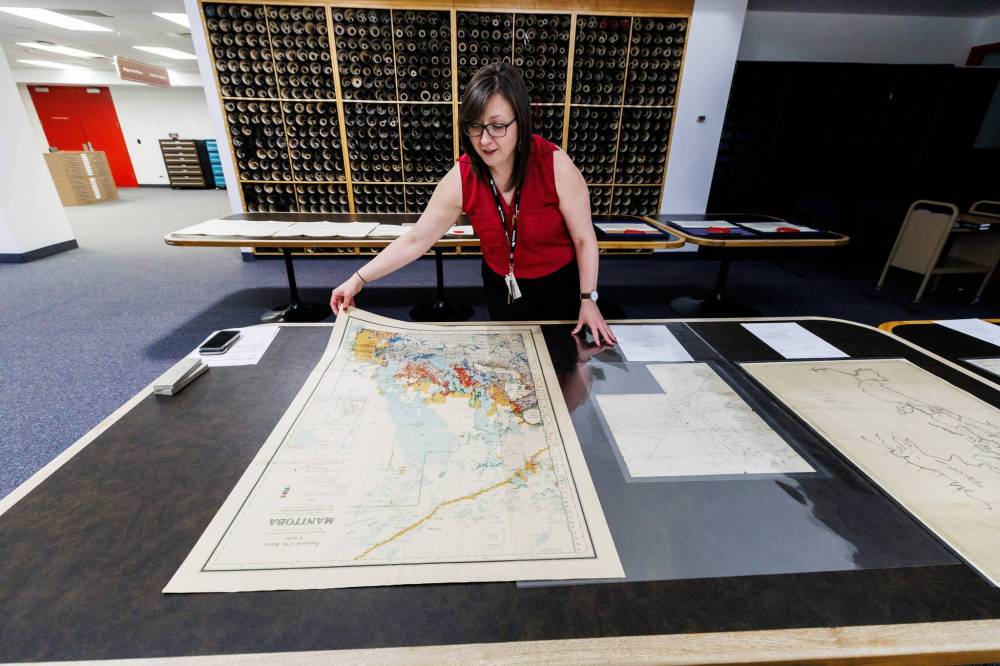 MIKE DEAL / FREE PRESS
Michelle Rydz, archivist with Hudson’s Bay Company Archives, lays out a 1921 map that shows the disposition of land in Manitoba.