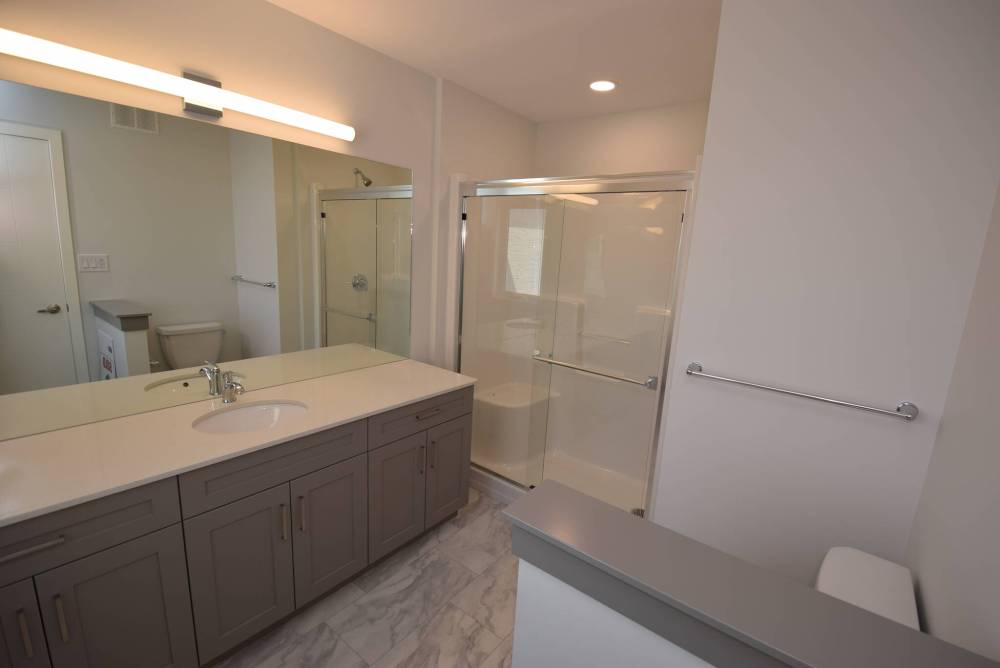 Spacious and wonderfully stylish, the primary bedroom’s ensuite offers a marble-style vinyl tile floor, five-foot walk-in shower and a huge vanity.