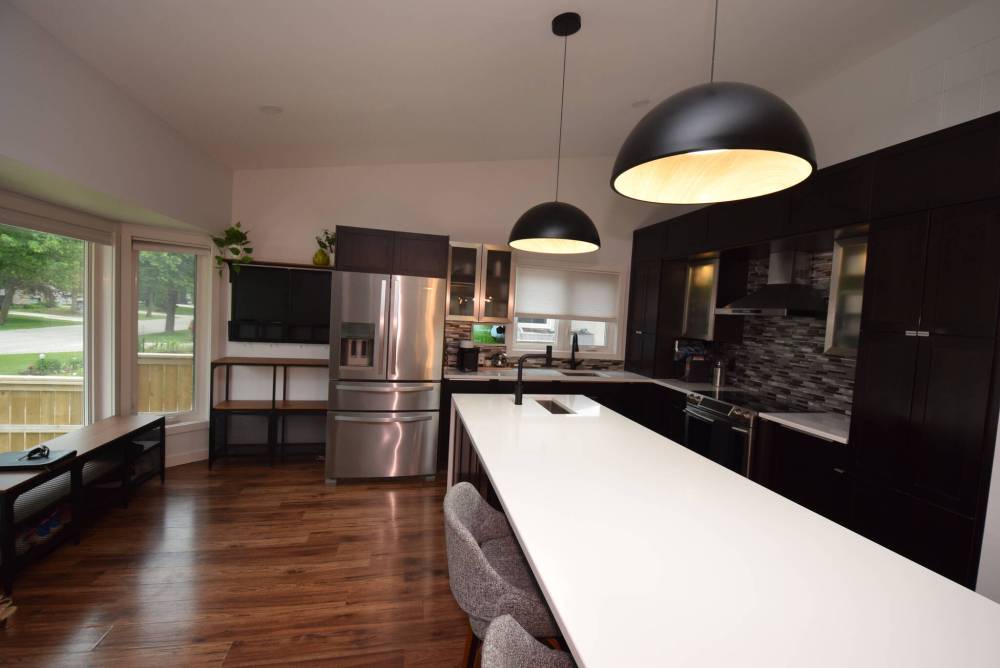 Modern and functional, the island kitchen offers quartz countertops, espresso maple and stainless Euro cabinets, a tile backsplash, newer flooring and a pantry with pullouts.