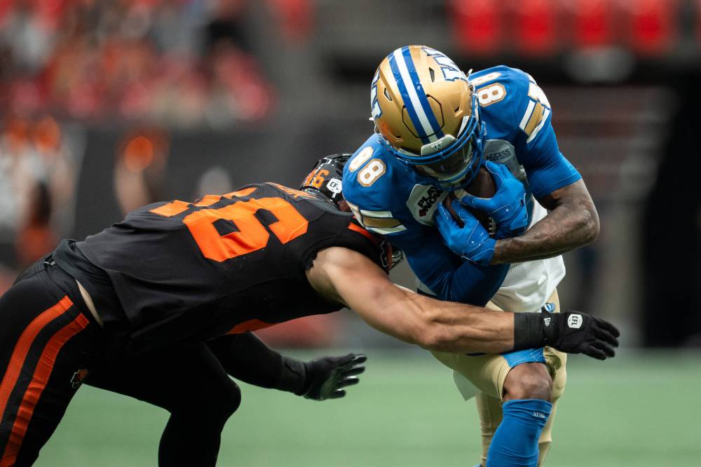 B.C. Lions’ Ben Hladik, left, tackles Winnipeg Blue Bombers’ Keric Wheatfall (88) during the first half of a CFL football game in Vancouver, on Saturday, June 21, 2025. THE CANADIAN PRESS/Ethan Cairns