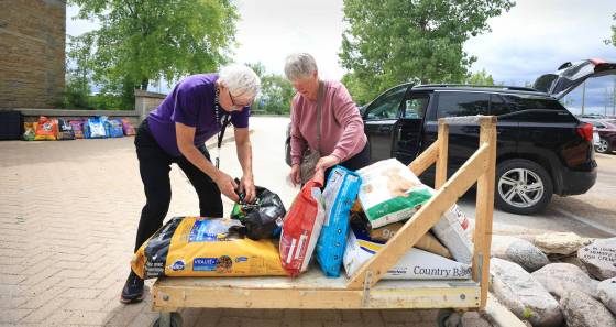Evacuee Berndina McLean of Bakers Narrows near Flin Flon, picks up some free dog food for her two dogs with the help of Winnipeg Humane Society volunteer Ken Lewicki, Monday. (Ruth Bonneville / Free Press)