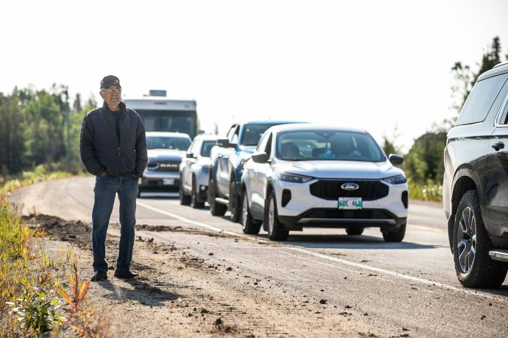 MIKAELA MACKENZIE / FREE PRESS
                                Norm Madland gets out of his car to check out the lineup of vehicles lined up on Highway 10 as wildfire evacuees return to Flin Flon on Wednesday morning.