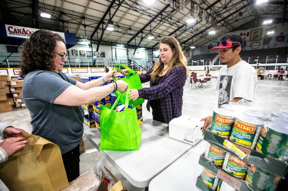 MIKAELA MACKENZIE / FREE PRESS
                                Colleen Tower (left) helps Creighton residents Patricia Dallas and Clemence Roberts with the food bank items at the Whitney Forum.