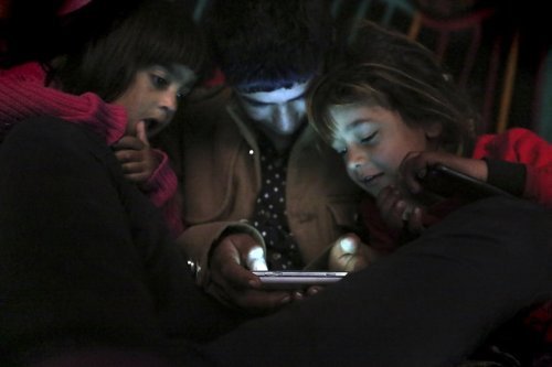 FILE - Children from Yazidi families, displaced by Islamic State group militants, look at a smartphone in a partially constructed building in Dohuk, northern Iraq, Dec. 10, 2014. (AP Photo/Seivan Selim, File)
