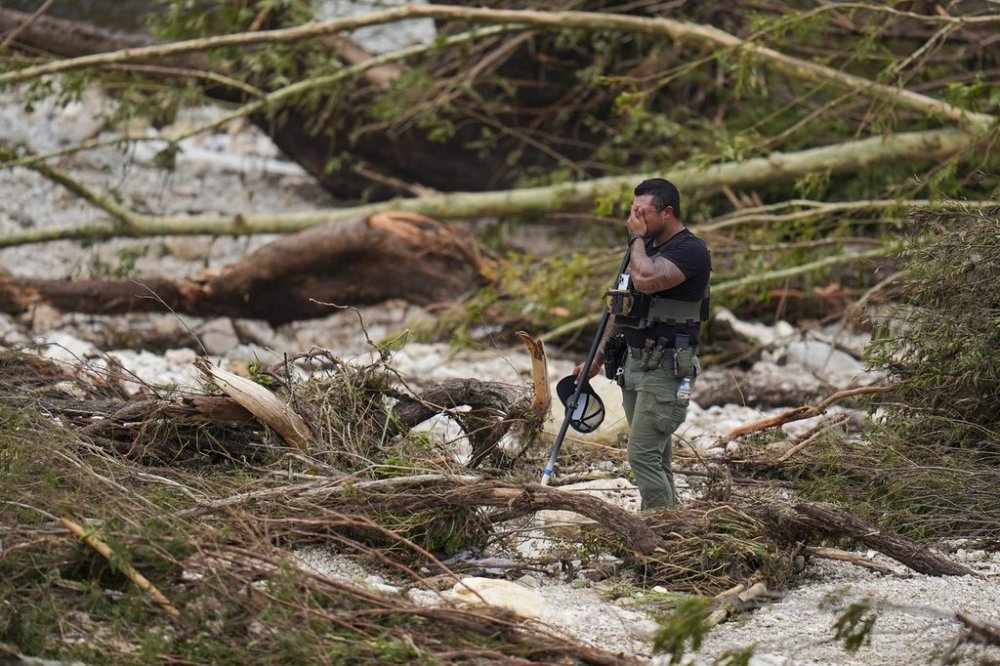 A Sheriff's deputy pauses while combing through the banks of the Guadalupe River near Camp Mystic after a flash flood swept through the area Saturday, July 5, 2025, in Hunt, Texas. (AP Photo/Julio Cortez)