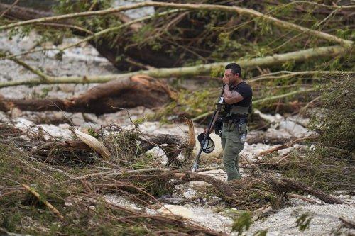 A Sheriff's deputy pauses while combing through the banks of the Guadalupe River near Camp Mystic after a flash flood swept through the area Saturday, July 5, 2025, in Hunt, Texas. (AP Photo/Julio Cortez)