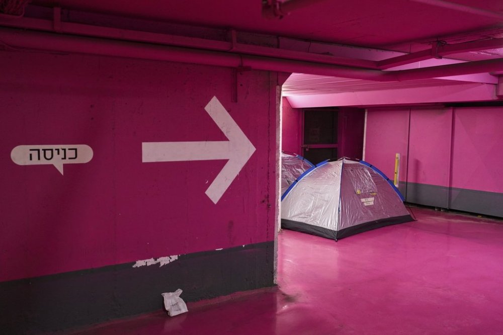 Sleeping tents are placed in an underground parking garage used as a shelter from missile strikes from Iran, in Tel Aviv, Israel, Saturday, June 21, 2025. Writing in Hebrew reads