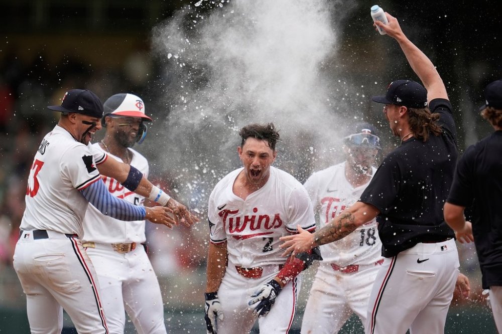 Minnesota Twins' Brooks Lee (2) celebrates with teammates after reaching on a winning infield RBI bunt to score teammate Byron Buxton during the ninth inning of a baseball game against the Tampa Bay Rays Saturday, July 5, 2025, in Minneapolis. (AP Photo/Abbie Parr)