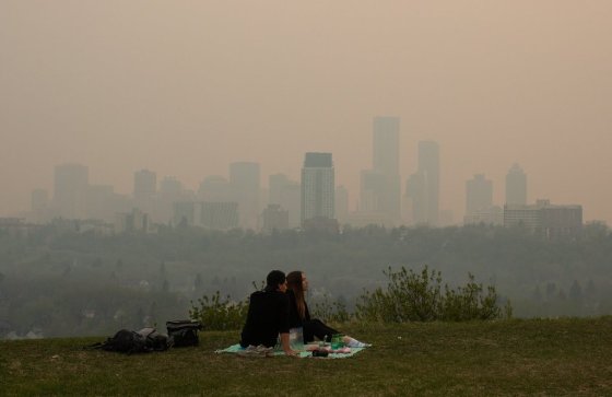 Smoke from wildfires blankets the city as a couple has a picnic in Edmonton in 2024. (Jason Franson / The Canadian Press files)