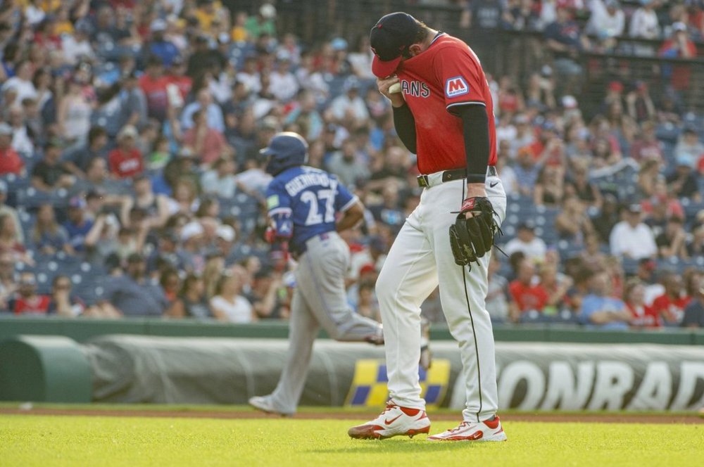 Cleveland Guardians starting pitcher Gavin Williams, front, reacts after giving up a solo home run as Toronto Blue Jays' Vladimir Guerrero Jr. (27) rounds the bases during the fourth inning of a baseball game, Wednesday, June 25, 2025, in Cleveland. (AP Photo/Phil Long)