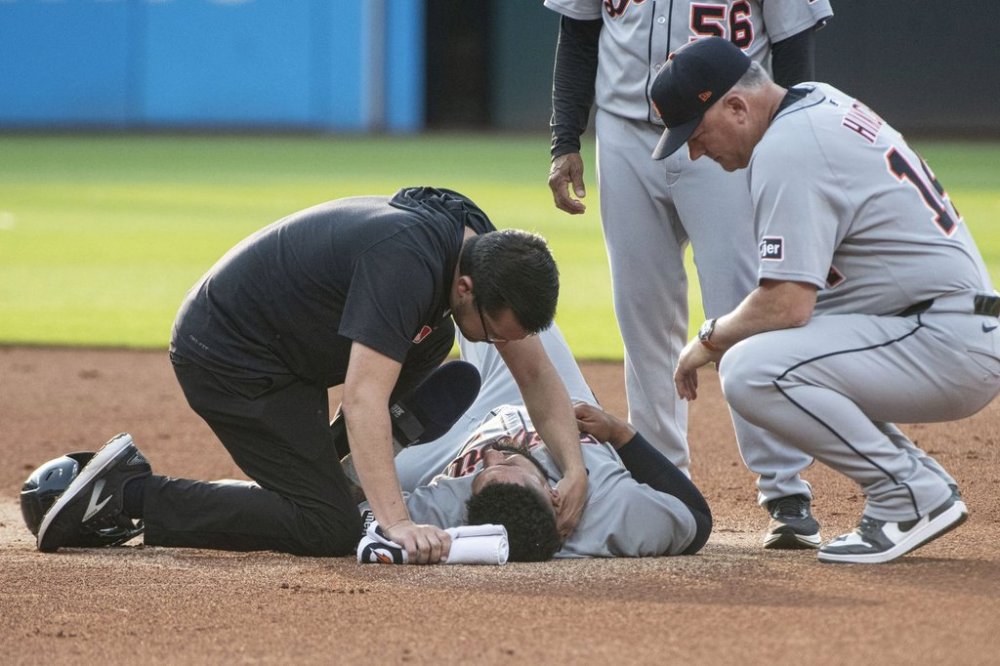 Detroit Tigers' Gleyber Torres, center bottom, is tended to after an injury at second base as manager A.J. Hinch, right, looks on during the first inning of a baseball game against the Cleveland Guardians, Saturday, July 5, 2025, in Cleveland. Torres was taken out of the game. (AP Photo/Phil Long)