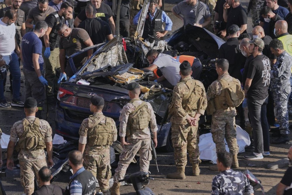Civil Defense workers and Lebanese soldiers gather around a destroyed car that was hit in an Israeli drone strike in Khaldeh town, south of Beirut, Lebanon, Thursday, July 3, 2025. (AP Photo/Hussein Malla)
