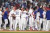Texas Rangers' Marcus Semien, center with white gloved hand raised, is congratulated by teammates after driving in the winning run in the 10th inning of a baseball game against the Seattle Mariners, Saturday, June 28, 2025, in Arlington, Texas. (AP Photo/Tony Gutierrez)