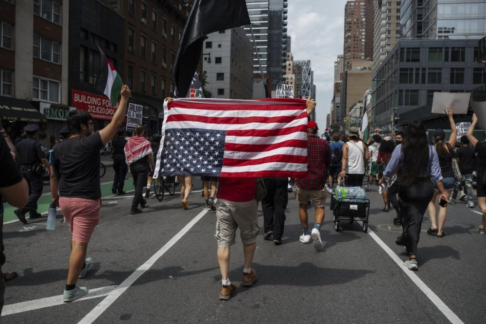 Protester carries an upside down American flag during a protest against U.S. strikes on Iran, Sunday, June 22, 2025, in New York. (AP Photo/Olga Fedorova)