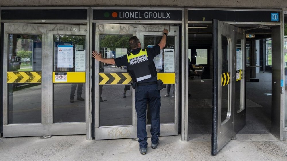 A special constable from the Société de transport de Montréal (STM) locks the doors to the metro station due to the strike from STM maintenance workers in Montreal on Monday, June 9, 2025. THE CANADIAN PRESS/Christinne Muschi