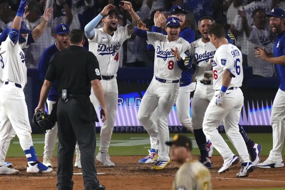 Los Angeles Dodgers' Will Smith, second from right, celebrates with teammates after hitting a walk-off home run as San Diego Padres third baseman Manny Machado walks off the field during the ninth inning of a baseball game, Wednesday, June 18, 2025, in Los Angeles. (AP Photo/Mark J. Terrill)