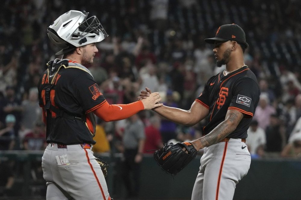 San Francisco Giants catcher Patrick Bailey (14) and pitcher Camilo Doval celebrate after defeating the Arizona Diamondbacks during a baseball game, Wednesday, July 2, 2025, in Phoenix. (AP Photo/Rick Scuteri)