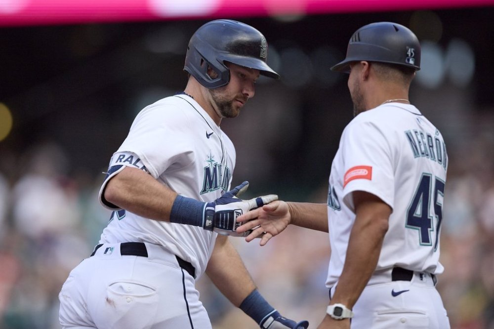 Seattle Mariners' Cal Raleigh is greeted by third base coach Kristopher Negrón on a grand slam off Boston Red Sox starting pitcher Walker Buehler during the second inning of a baseball game, Tuesday, June 17, 2025, in Seattle. (AP Photo/John Froschauer)
