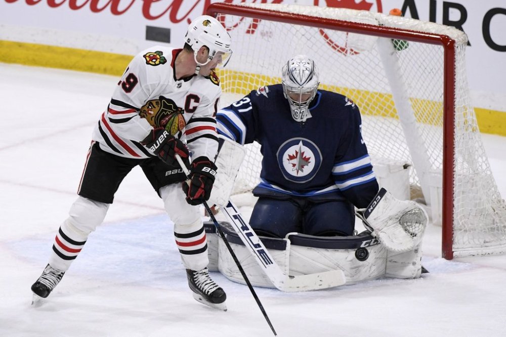 Winnipeg Jets' goaltender Connor Hellebuyck (37) makes a save on Chicago Blackhawks' Jonathan Toews (19) during third period NHL action in Winnipeg on Sunday, Feb. 16, 2020. Toews is the newest member of the Jets after signing a one-year deal with the team after not playing for two full seasons. THE CANADIAN PRESS/Fred Greenslade